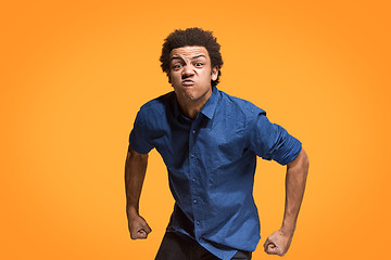 Image showing The young emotional angry man screaming on orange studio background