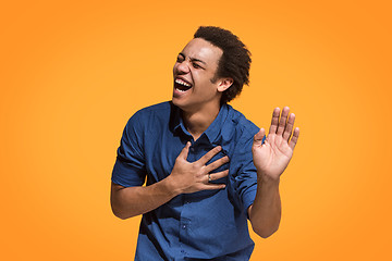 Image showing The happy business man standing and smiling against orange background.