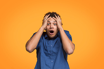 Image showing The young emotional angry man screaming on orange studio background