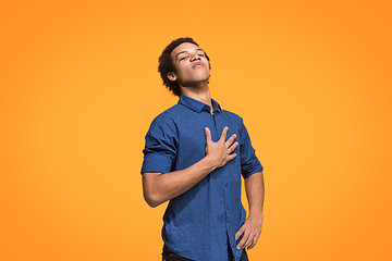 Image showing Beautiful male half-length portrait isolated on orange studio backgroud. The young emotional surprised man