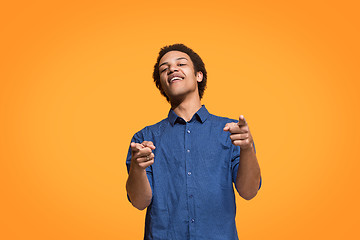 Image showing The happy business man point you and want you, half length closeup portrait on orange background.