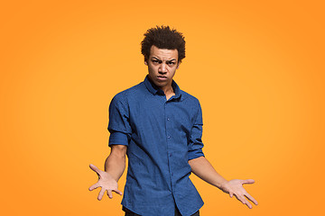 Image showing Beautiful male half-length portrait isolated on orange studio backgroud. The young emotional afro man