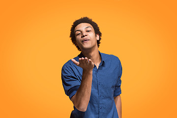 Image showing Portrait of attractive afro man with kiss isolated over orange background