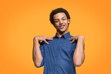 Image showing Beautiful male half-length portrait isolated on orange studio backgroud. The young emotional surprised man