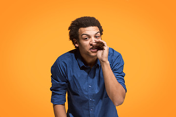 Image showing Isolated on orange young casual man shouting at studio