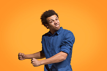 Image showing The young emotional angry man screaming on orange studio background