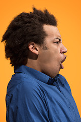 Image showing Beautiful male half-length portrait isolated on orange studio backgroud. The young emotional surprised man