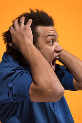 Image showing The young emotional angry man screaming on orange studio background