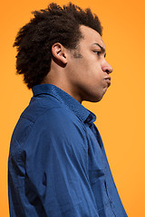 Image showing The young emotional angry man screaming on orange studio background