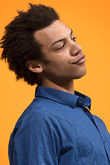 Image showing Beautiful male half-length portrait isolated on orange studio backgroud. The young emotional surprised man