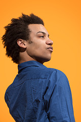 Image showing Beautiful male half-length portrait isolated on orange studio backgroud. The young emotional surprised man