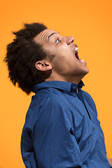 Image showing The young emotional angry man screaming on orange studio background