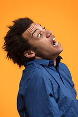 Image showing The young emotional angry man screaming on orange studio background