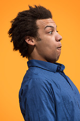 Image showing The young attractive man looking suprised isolated on orange