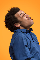 Image showing The young emotional angry man screaming on orange studio background