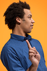 Image showing Beautiful male half-length portrait isolated on orange studio backgroud. The young emotional surprised man