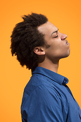 Image showing The young emotional angry man screaming on orange studio background