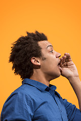 Image showing Isolated on orange young casual man shouting at studio