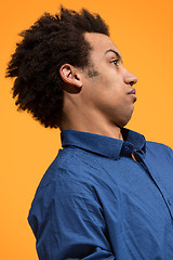 Image showing Beautiful male half-length portrait isolated on orange studio backgroud. The young emotional surprised man