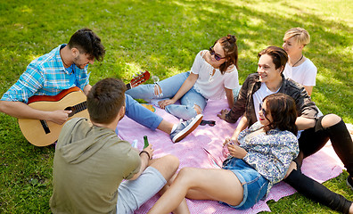 Image showing friends playing guitar at picnic in summer park