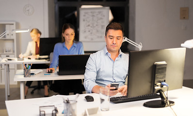 Image showing man with smartphone working at night office