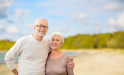 Image showing happy senior couple hugging over beach background