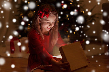 Image showing smiling girl opening christmas gift at night