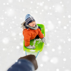 Image showing happy boy riding sled on snow in winter
