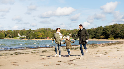 Image showing happy family running along autumn beach