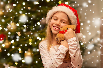 Image showing smiling girl in santa hat with christmas gift