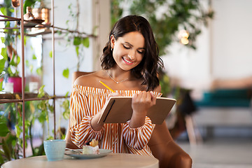 Image showing happy woman with notebook at coffee shop or cafe