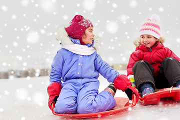 Image showing happy little girls on sleds outdoors in winter