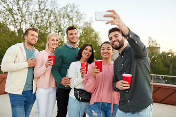 Image showing friends with drinks taking selfie at rooftop party