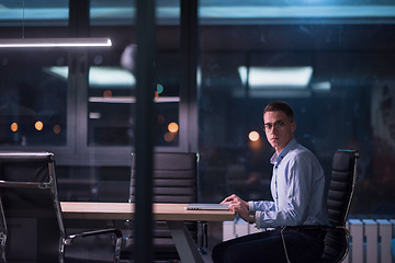 Image showing man working on laptop in dark office