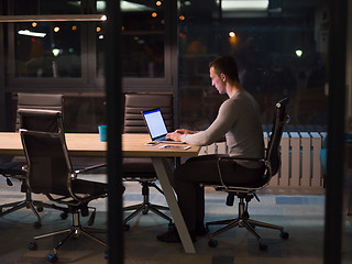 Image showing man working on laptop in dark office