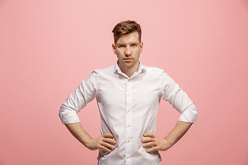 Image showing The serious businessman standing and looking at camera against pink background.