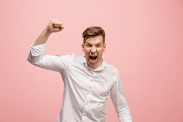 Image showing The young emotional angry man screaming on pink studio background