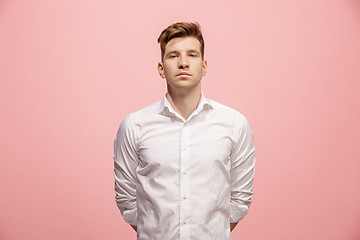 Image showing The serious businessman standing and looking at camera against pink background.