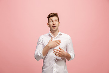 Image showing Beautiful male half-length portrait isolated on pink studio backgroud. The young emotional surprised man