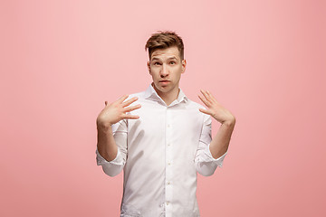 Image showing Beautiful male half-length portrait isolated on pink studio backgroud. The young emotional surprised man