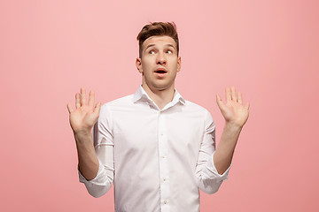 Image showing Beautiful male half-length portrait isolated on pink studio backgroud. The young emotional surprised man