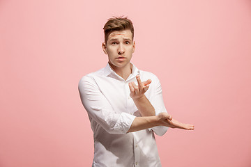 Image showing Beautiful male half-length portrait isolated on pink studio backgroud. The young emotional surprised man