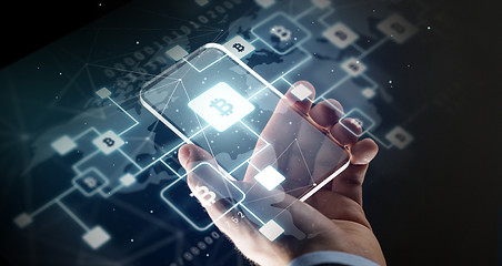 Image showing close up of hand with smartphone and bitcoin