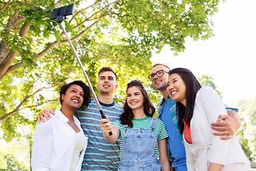 Image showing happy friends taking photo by selfie stick at park