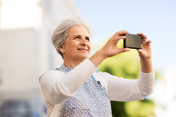 Image showing senior woman photographing by smartphone in city