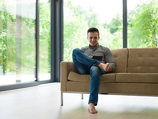 Image showing man on sofa using tablet computer