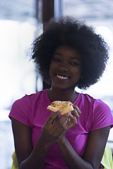 Image showing woman with afro hairstyle eating tasty pizza slice