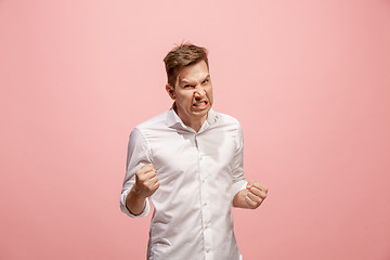 Image showing The young emotional angry man screaming on pink studio background