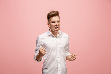 Image showing The young emotional angry man screaming on pink studio background