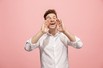 Image showing Isolated on pink young casual man shouting at studio